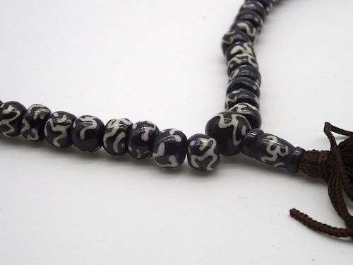 Mala budista pintado de negro con el mantra OM
